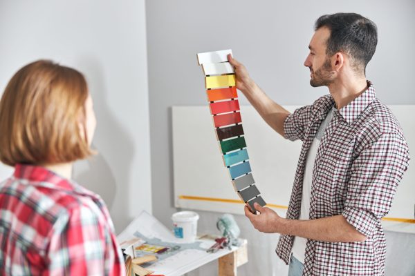 Blonde woman looking at a colored medium-density fiberboard sample kit in the male worker hands