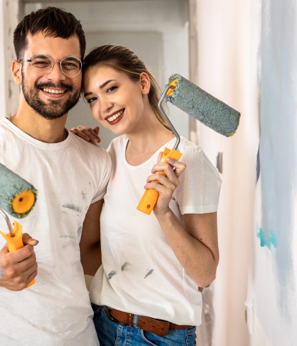 Young couple painting wall in their home.